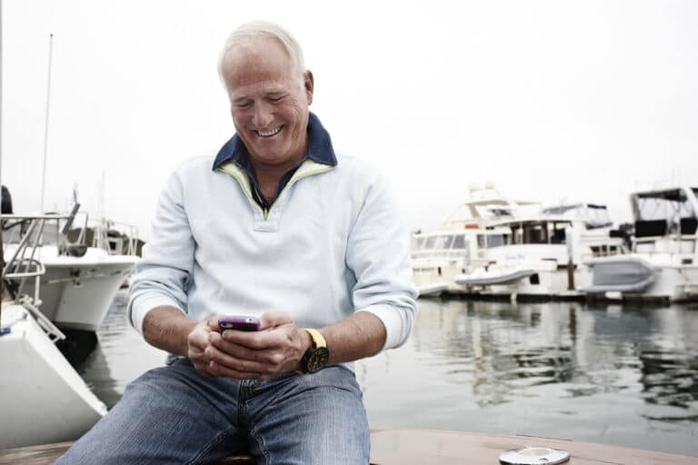 Man using cell phone in marina, How to Sell a Boat Fast - The Ultimate Checklist for Boat Owners