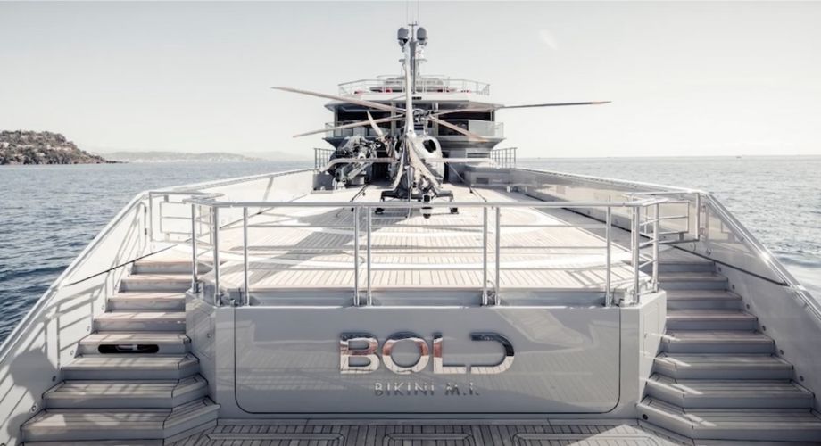 Bold Silver Yacht with two staircases view in the ocean. Explore the Bold 85M Silver Yacht at the Antigua Yacht Show with Camille Medina and Captain Benn, featuring luxury and a world-class crew.