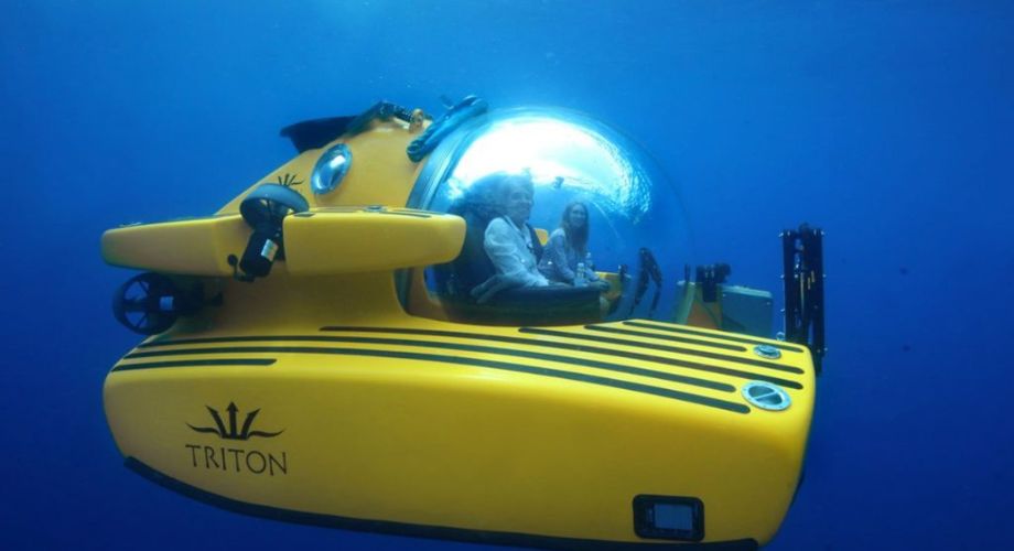 Two people inside a submarine diving into the ocean.