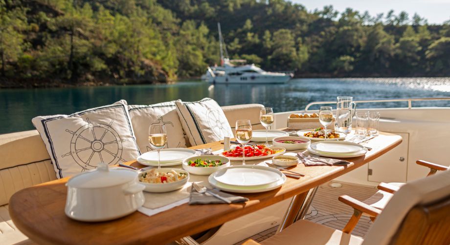 The outdoor table on the deck of a luxury yacht. Explore pros & cons of a cruise ship vs. yacht. Compare charter cruise options, exclusive amenities, & costs for ultimate luxury sea escape.