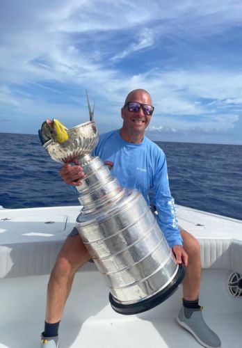 A man holding a trophy and sitting on a luxury yacht.
