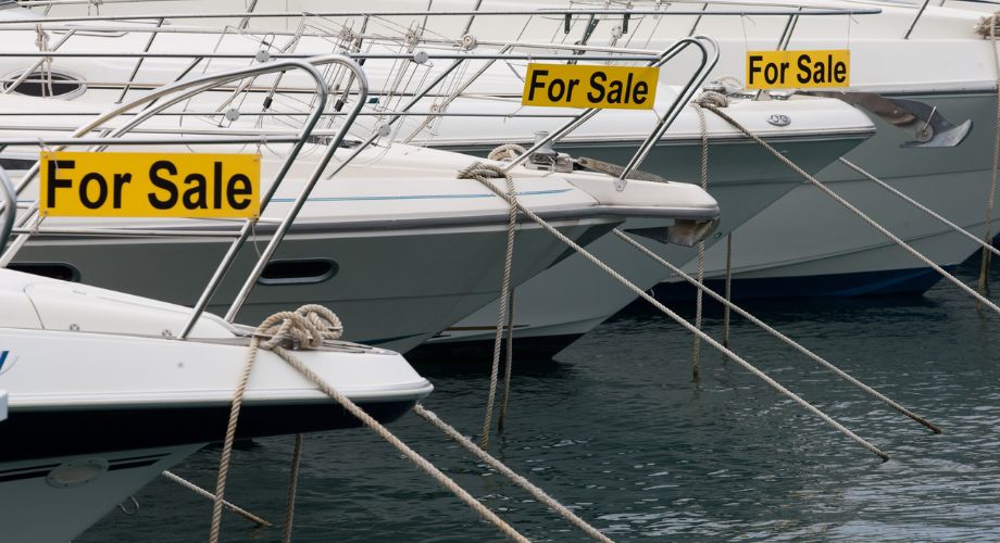 Yachts docked in the ocean with a for sale sign on them.
