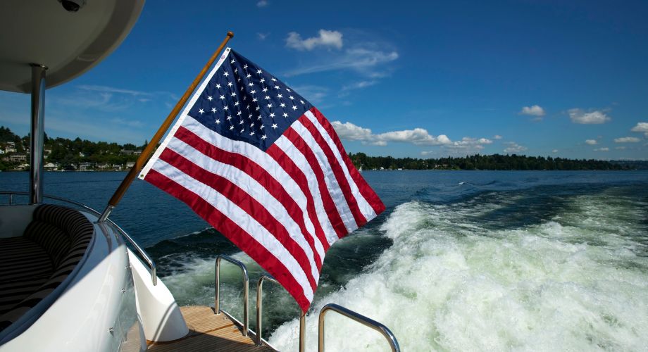 A yacht sailing in the ocean with a USA flag registered as its' yacht flag. Learn how to choose your yacht flag, understand the flag's meaning, and explore the best boat flags for legal and cultural purposes.