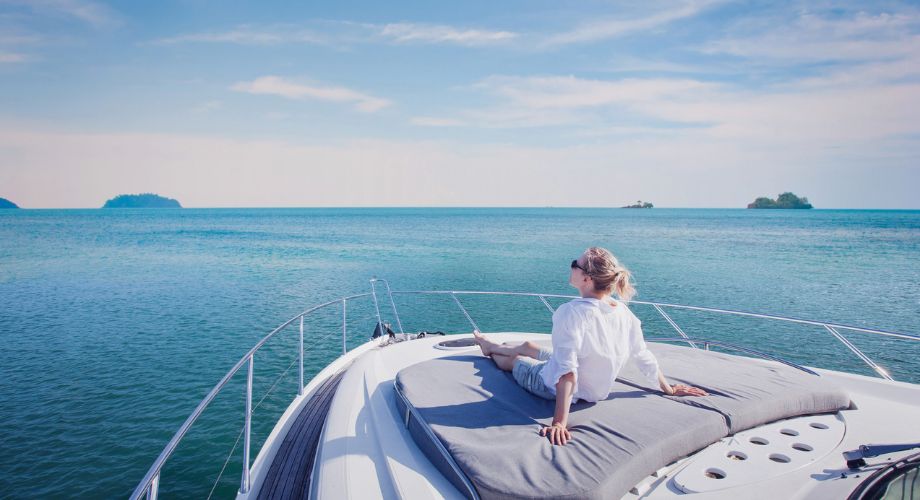 A woman sitting on a sailing luxury vessel outdoor deck.