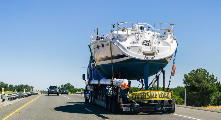 A yacht being transported on the back of a yacht trailer.