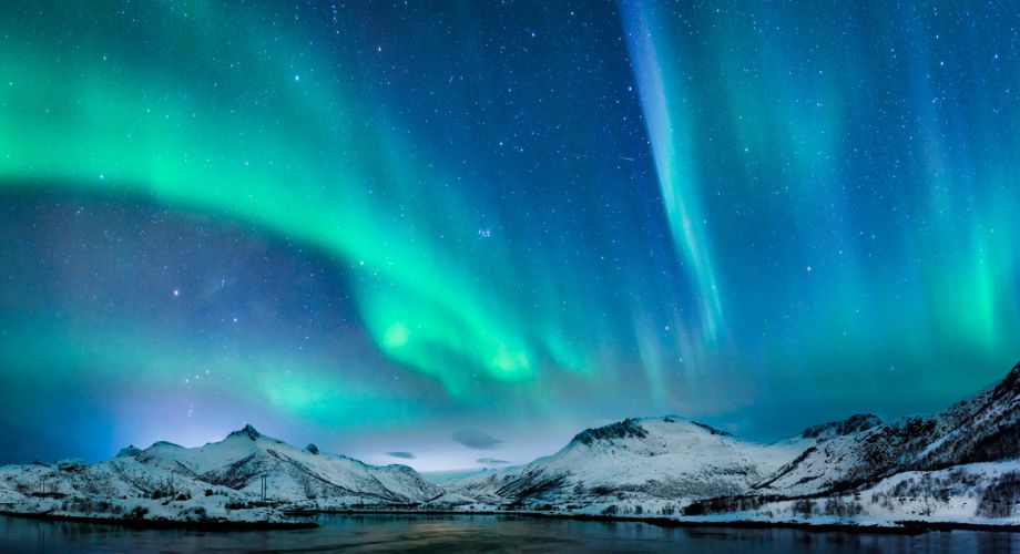 A breathtaking display of the Northern Lights dances across a star-studded sky above snow-covered mountains and a serene, reflective lake. Explore the global yacht charter market expansion and how evolving trends are reshaping demand and destinations.