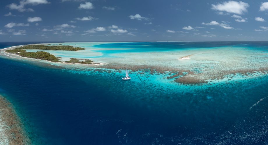 A pristine tropical atoll with vibrant turquoise waters, lush islets, and a solitary sailboat drifting peacefully in the lagoon, captures the essence of a near-paradise escape. Explore how solar yachts and boat solar panels transform marine travel with clean, renewable energy, efficiency, and sustainability. 
