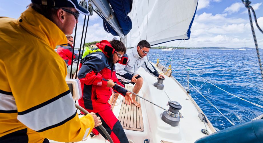 A group of people on a superyacht that's sailing in the ocean during a superyacht regatta.
