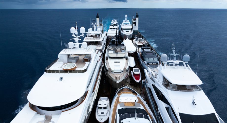 A fleet of luxury yachts is tightly packed on a specialized transport vessel in the open sea, illustrating an international yacht delivery in progress. Learn how to prepare for yacht delivery, discover top yacht delivery services, and understand key shipping options for your yacht.