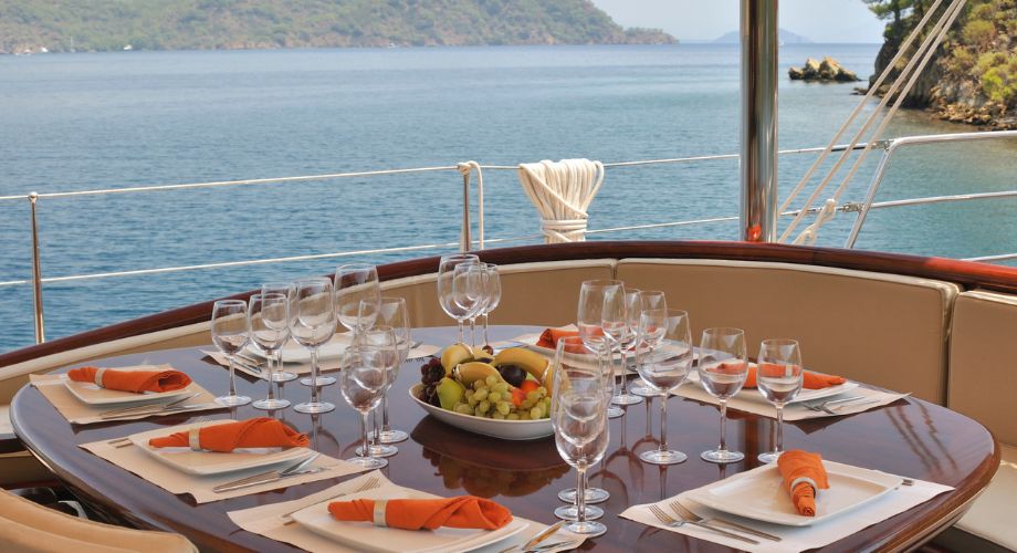 An outdoor dining table on a luxury yacht that's sailing in the ocean.