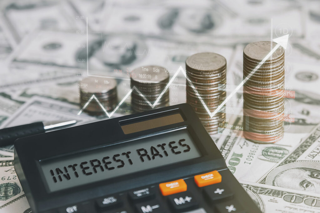 A financial concept with a calculator displaying "INTEREST RATES," stacks of coins, US dollar bills, and a rising line graph symbolizing increasing interest rates and economic growth. Explore how bank interest rates affect yacht lending. Compare loan options, use calculators, and learn how to finance a yacht purchase.