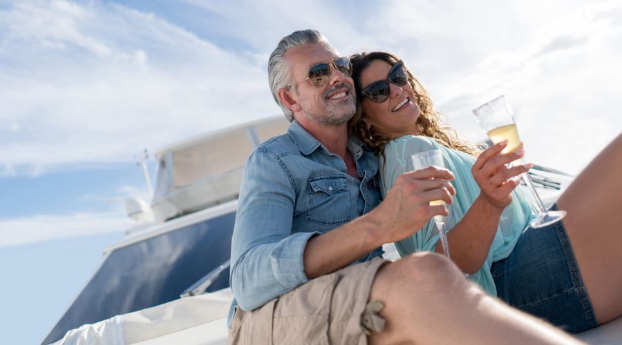 A couple drinking wine and enjoying a yacht mortgage that's sailing in the ocean. Explore the pros & cons of yacht mortgage vs. leasing. Compare yacht mortgage rates, leasing terms, and financing options to fit your budget.