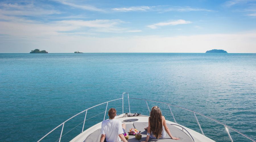 A couple on a luxury yacht sailing in the ocean. Explore the pros & cons of yacht mortgage vs. leasing. Compare yacht mortgage rates, leasing terms, and financing options to fit your budget.