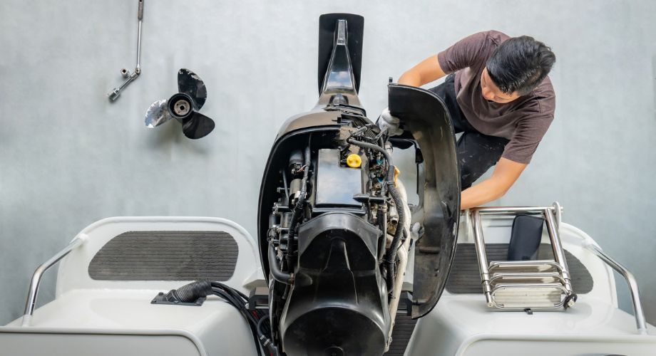 Yachts & Boat Warranty Guide: Coverage, Claims & Costs | YATCO A technician works on the engine of a boat, likely performing maintenance or repairs—an essential part of services often included under a boat warranty or yacht warranty coverage.