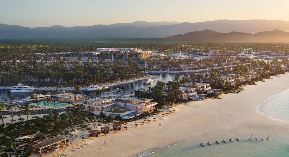 A luxurious coastal resort community featuring beachfront villas, a marina with yachts, lush greenery, and modern architecture set against a backdrop of mountains at sunset.