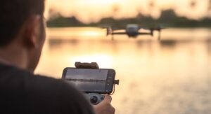 The drone pilot's hand is holding a remote control to control the drone. Explore how drone technology is transforming the yachting experience—from aerial filming and security to guest services and innovation at sea.
