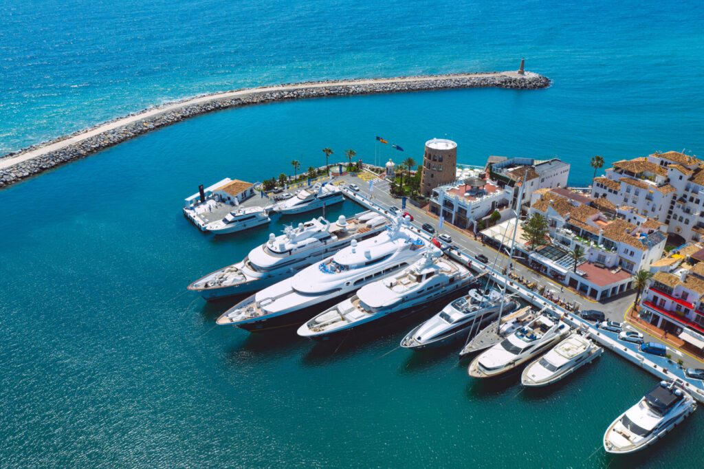 Aerial top view of luxury yachts in Puerto Banus marina, Marbella, Spain as a last minute yacht charter destination. Find a last-minute yacht charter deal. Explore the options, risks, and destinations for spontaneous luxury yacht rentals.