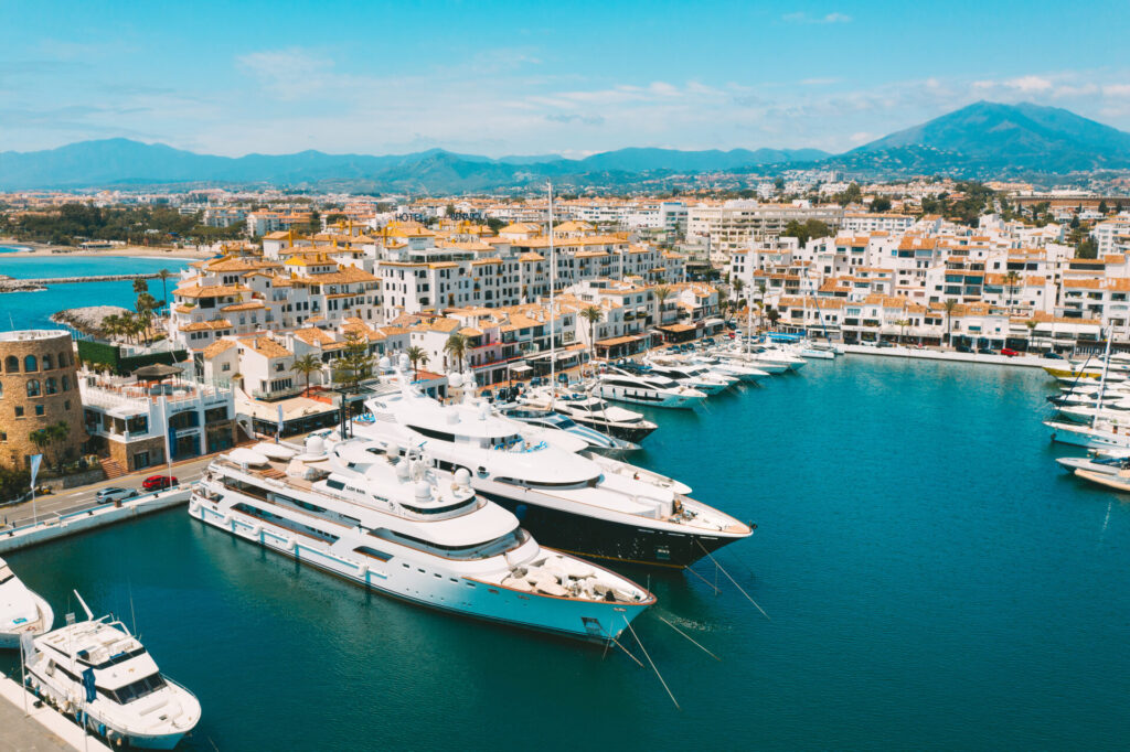 Mega Yacht vs Superyacht | Differences, Sizes & Prices | YATCO Aerial top view of luxury mega yacht vs superyacht in Puerto Banus marina, Marbella, Spain. Discover the difference between a mega yacht vs superyacht, from sizes and features to prices and the world’s largest vessels.