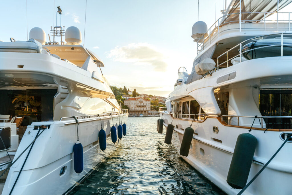 Large luxury yachts moored in the port of a tourist Mediterranean city in sunset light.