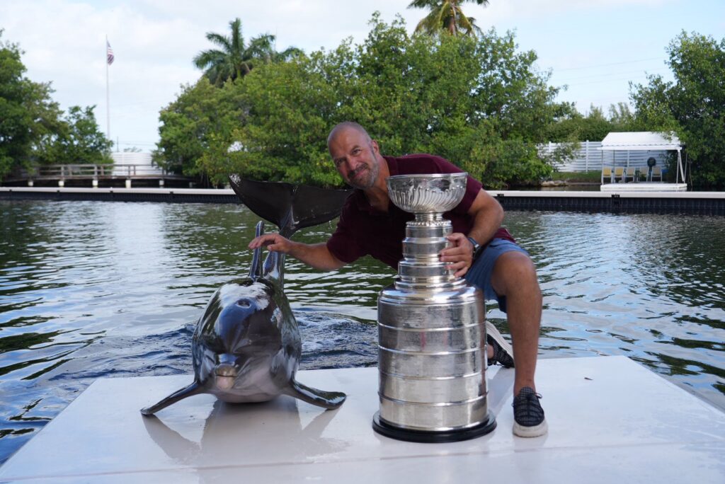 A man next to a trophy and a dolphin.