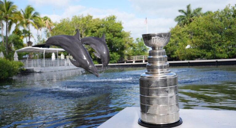 Two dolphins swimming next to a trophy. The Stanley Cup made a splash in the Florida Keys as part of the Florida Panthers’ ongoing championship celebration.