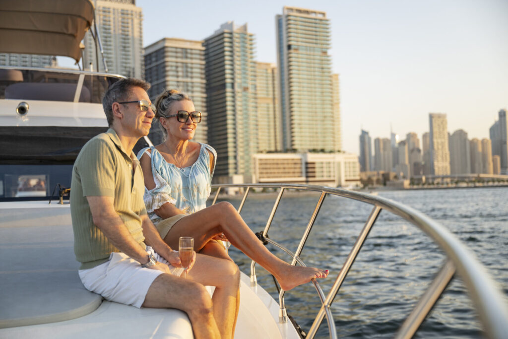 Yacht Charter License | Legal Requirements | Regulations | YATCO Cheerful couple in their 50s with wine sitting on private yacht and relaxing.