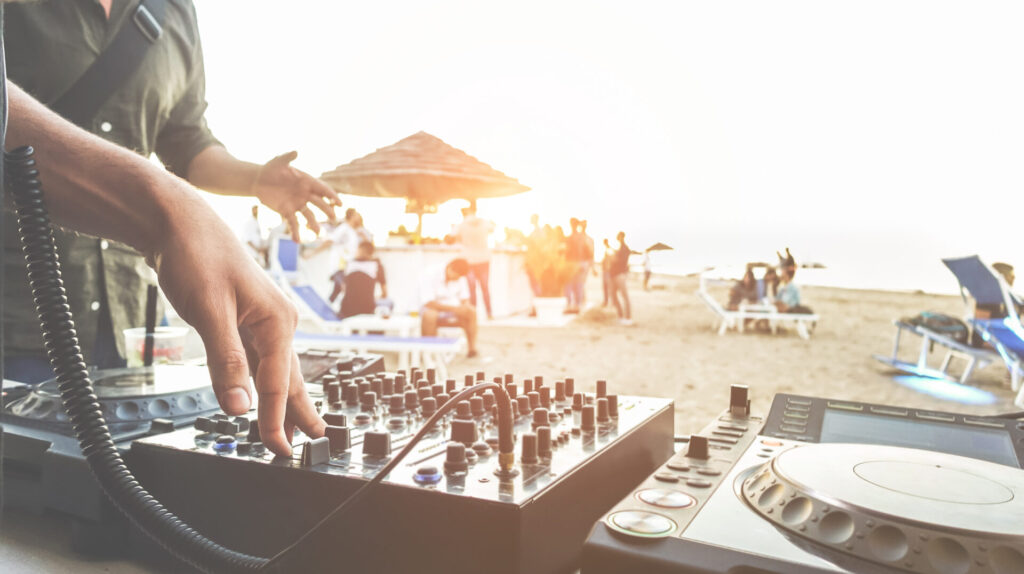 Dj mixing at sunset beach party in summer vacation outdoor.