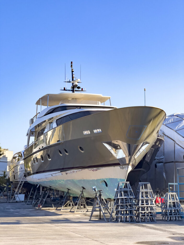 Yacht Cost Breakdown | Buying, Owning & Maintenance | YATCO A Boat yard with winter storage of power yachts and sailing boats, placed on blocks. Shipyard professional services for washing, painting and motor boat maintenance.