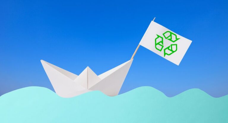 Blank origami paper boat floating on the blue paper wave against clear sky representing yacht recycling.