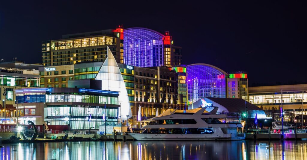 Yachts and Boats in Washington DC | Verified Listings | YATCO Buildings and a boat on the shore of the Potomac River at night, in National Harbor, Maryland.