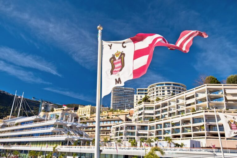 Yacht Club de Monaco flag and headquarters view. Exclusive yacht clubs are more than private marinas, they are global networking hubs where UHNWIs connect and cultivate influence.