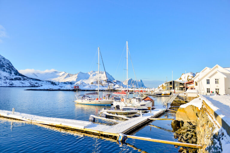 Marina in a bay at Hamn on the island Senja in Northern Norway on a winter day with fishing boats and sailing boats moored at the dock. Discover the finest Scandinavian yachts from leading builders. Learn about northern yacht craftsmanship and find sailing yachts for sale.