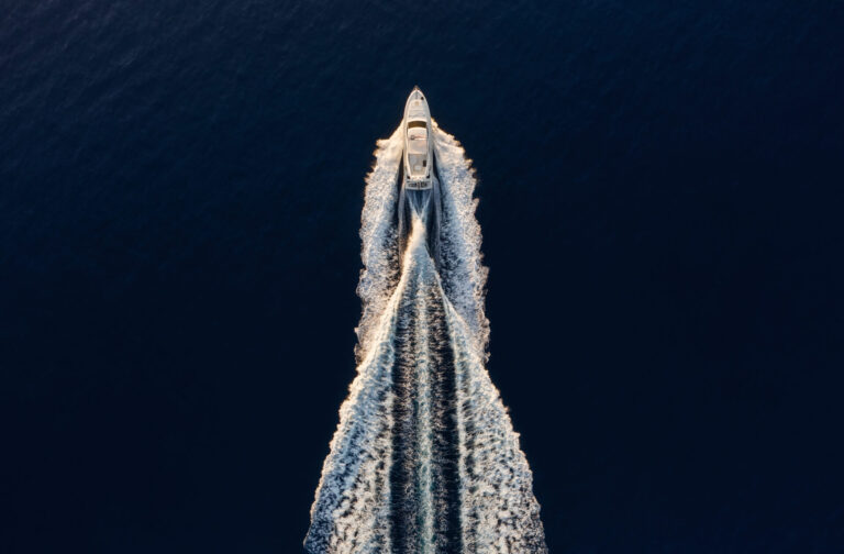 Aerial view on fast boat on blue Mediterranean sea at sunny day. Demystify superyacht ownership with insights on financing, loans, and insurance essentials for a secure investment.