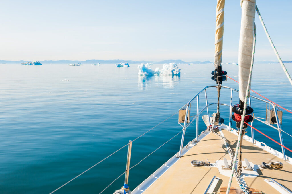 Best Yachts for Global Yacht Circumnavigation | YATCO A luxury yacht sailing among icebergs off Greenland in the Atlantic Ocean as part of a world yacht circumnavigation.