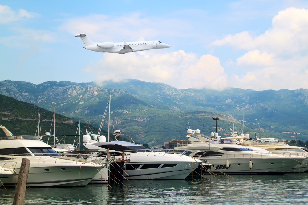 An airplane flying over the sea where luxury yachts are docked.