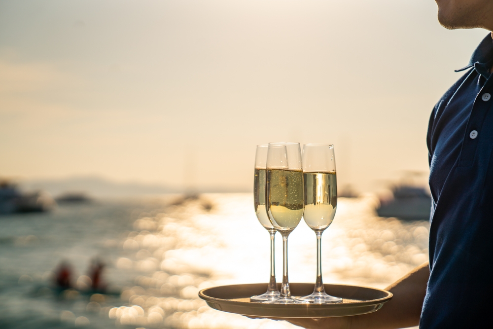 Is Yachting Keeping Up with Luxury Hospitality | YATCO A waiter serving champagne glasses.