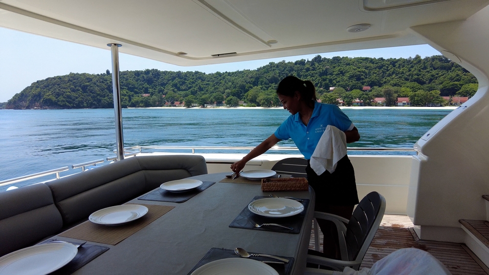 Future of Yacht Crew 2026 | Salaries, Training & Trends | YATCO A yacht crew member placing plates on a yacht's dining table.