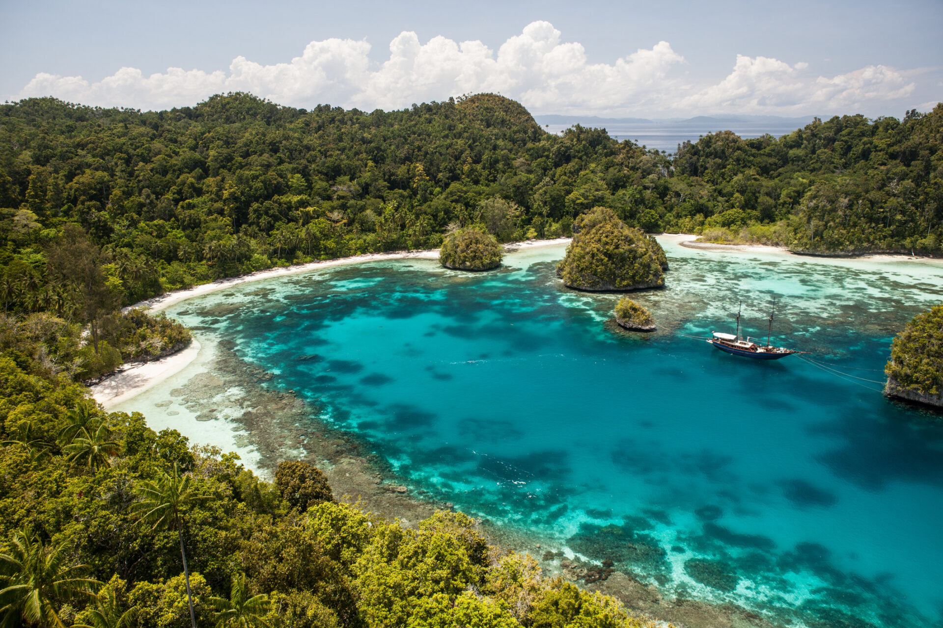 Small Yacht Trends 2026 | Owner-Operator Options | YATCO A boat in a peaceful tropical lagoon in Raja Ampat, Indonesia