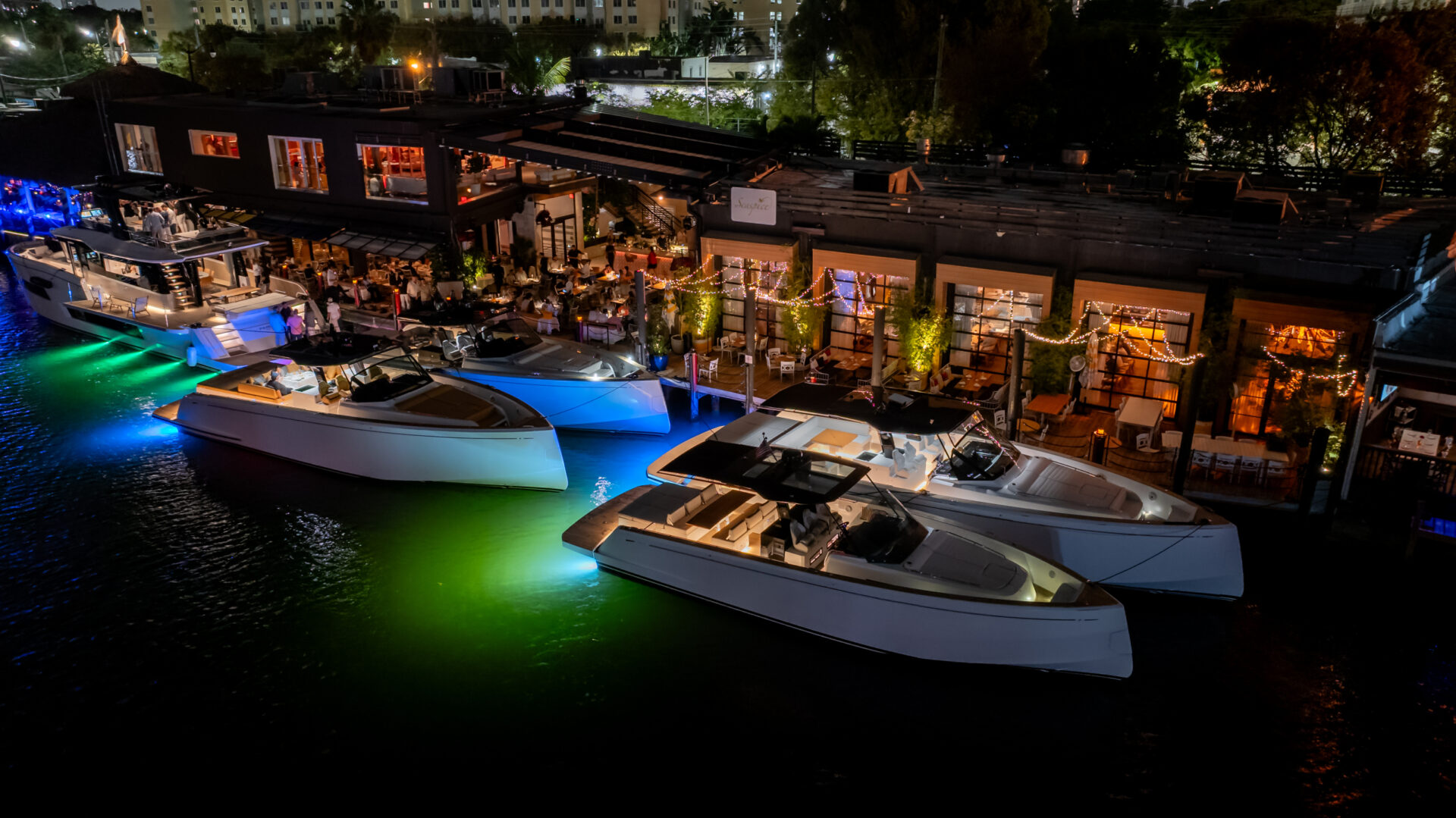 Small Yacht Trends 2026 | Owner-Operator Options | YATCO Luxury boats docked beside a waterfront restaurant at night in Miami